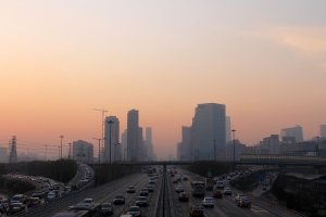 Varios coches circulan por una gran urbe con aire contaminado
