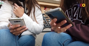 Dos adolescentes consultan su teléfono móvil