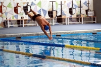 Detalle de la piscina con nadador al frente y su característico fondo de azulejos al fondo.
